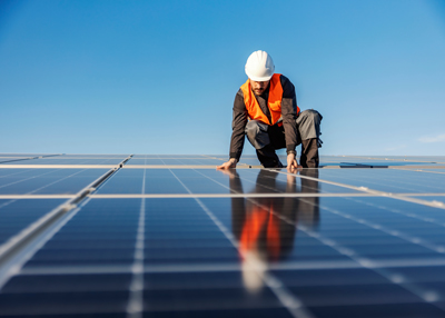 man in safety gear inspecting solar panels on rooftop in bright sunlight focusing on renewable energy and solar technology